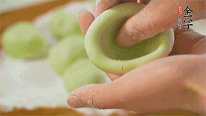 將均分的艾草面團搓成圓，挖一個窩，放入餡心，再搓成圓。