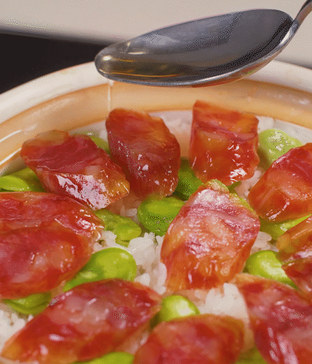 大米出現(xiàn)小孔時(shí)開蓋放香腸，往鍋邊淋入少許油，再燜煮8~10分鐘左右。