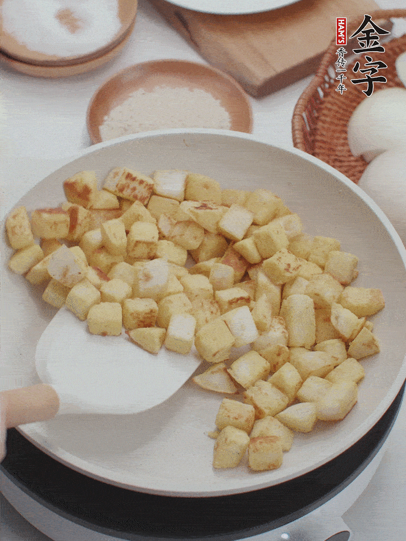 起鍋熱油，倒入饅頭丁，小火煎至蛋液凝固定型再翻面，饅頭丁部煎至金黃時(shí)盛起待用。