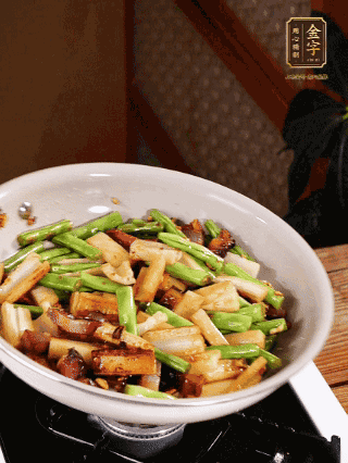 油熱下蒜末、干辣椒、醬肉煸炒出香味，依次下藕條、豆角翻炒均勻